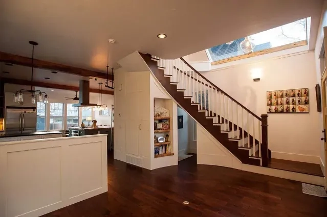 Modern home interior featuring a dark wood staircase, white cabinetry, and an open kitchen layout.